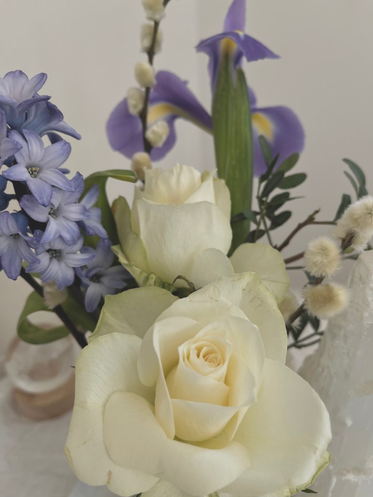A bouquet featuring white roses, blue hyacinths, and purple irises arranged elegantly.